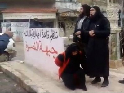 تجثو إمرأة خمسينية العمر على ركبتيها ليقوم عناصر من جبهة النصرة بإعدامها بتهمة الدعارة